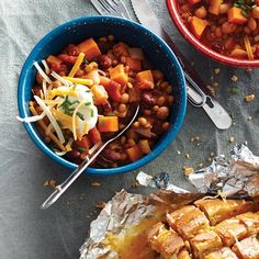 two bowls filled with food sitting on top of a table next to silverware and forks