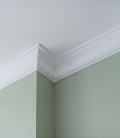 the corner of a room with green walls and white molding on the ceiling above