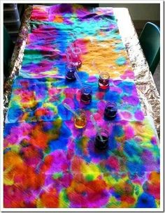 the table is covered with multicolored fabric and glasses are sitting on top of it