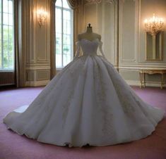 a white wedding dress on display in a room with chandeliers and windows,