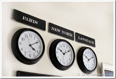 three clocks are hanging on the wall with paris and new york signs