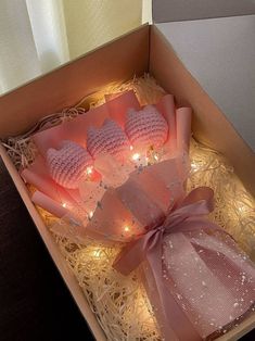 three pink heart shaped candles in a box with string lights on the sides and ribbon