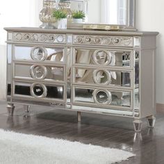 a silver mirrored cabinet with drawers and mirrors on the top, in front of a white rug