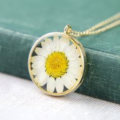 "A delightful and summery real, dried and pressed flower with the classic white petals and yellow centre, encased in resin and with a gold plated setting, all hung from a gold plated fine chain. The pendant measures 3cm (1.2\") high and across. Choose a chain length tailored to you  **Gifts And Treating Yourself** Each item is individually packaged in a 'The Pretty Ditty' gift box or reuseable cotton gift bag. All packages are shipped in a recycable cardboard box. We do not include any price rec Summer Pendant, Yellow Daisy Flower, Flower Necklace Gold, Daisy Yellow, White Petals, Pressed Flower Necklace, Cotton Gift Bag, Jewelry Post, White Daisy