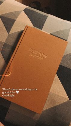 an orange book sitting on top of a couch next to a pillow with the words, there's always something to be grateful for