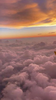 the view from an airplane window shows clouds and sunset in the sky, as seen from above