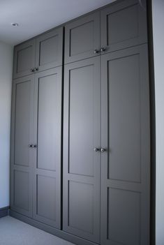 an empty room with gray cabinets and carpeted flooring on the ground, in front of a white wall