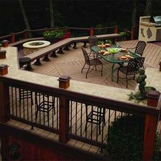 an outdoor deck with tables and chairs around the fire pit is lit up at night