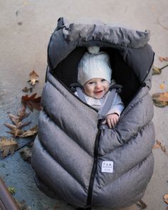 a baby in a sleeping bag on the ground