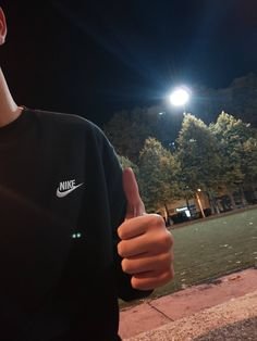 a man giving the thumbs up sign in front of a street light with trees and buildings in the background