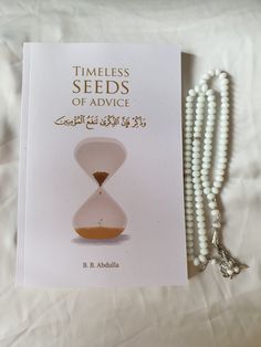 a book with beads and a necklace laying on top of it next to a white beaded necklace