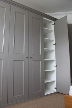 an open closet with shelves and doors on the bottom, in front of a bed