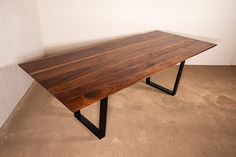 a wooden table with black metal legs on concrete flooring next to white brick wall