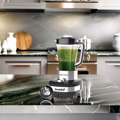 a blender filled with green liquid sitting on top of a counter in a kitchen