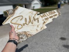 a person holding up a sign that says sully mellisa in gold lettering