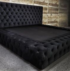 a black bed frame with tufted headboard and foot board in front of a wooden wall