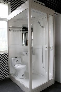 a white toilet sitting inside of a bathroom next to a walk in shower and sink