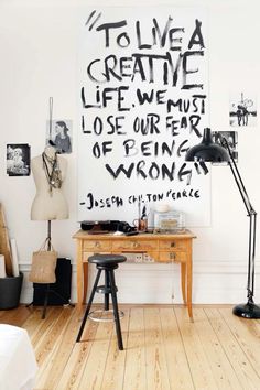 a wooden table sitting in front of a white wall with writing on the wall above it