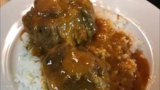 two meatballs covered in gravy over rice on a white plate with sauce