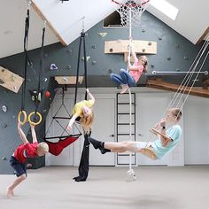 three children are playing in the gym with their hands up and one is holding a basketball hoop