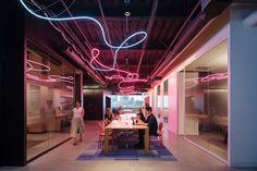 three people sitting at a table in an office with neon lights on the walls and floor