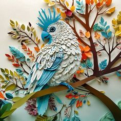 a paper cut bird sitting on top of a tree branch