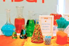 a table topped with lots of different colored bottles filled with liquid and candies next to each other