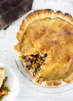 a pie sitting on top of a white plate next to a slice of pie in front of it