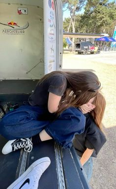 two people sitting in the back of a truck with their arms wrapped around each other