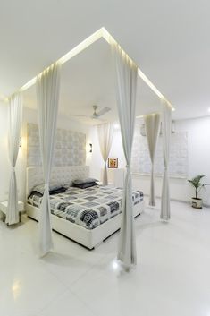 a bedroom with white walls and curtains on the ceiling is decorated in black and white