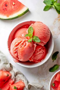 two bowls filled with watermelon ice cream next to slices of watermelon