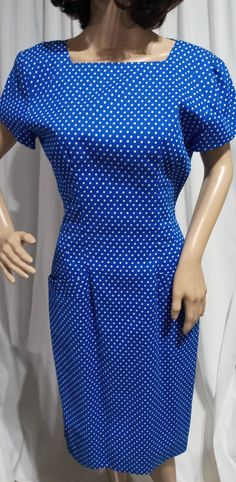 Vintage Blue and White Polka Dot Dress. 1980s does 1950's fitted silhouette with a straight cut neck and short sleeves. Elongated by princess seams. Cute polka dot pattern sprawled all over. Kick pleat in the back of the pencil cut skirt. Fully lined. Beautiful criss cross pattern on the back is created with strips of fabric pulled diagonally across the open back to the next button hole. Secured with a sculpted White and Gold button. Zipper and hook at the back waist. Perfect look for Spring and all Summer long; make sure to add a hat! Kamisato by Geary Roark. Size 6, Small.  *Blue lining has faded to Purple in some areas beneath arm pits. Pencil Cut Skirt, Criss Cross Pattern, Arm Pits, 50s Fashion Dresses, Vintage Blue And White, 50s Style, White Polka Dot Dress, Button Hole, Kick Pleat