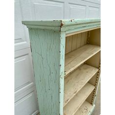 an old green bookcase with some rusted paint on the top and bottom shelves