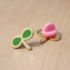 a pair of green and gold cufflinks with a pink button sitting on top of it