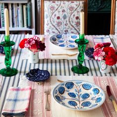 the table is set with plates, candles and flowers in vases on top of them