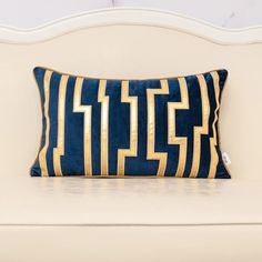 a blue and gold pillow sitting on top of a white couch