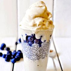 a blueberry milkshake is topped with whipped cream and blueberries on the side