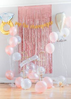 balloons and streamers are on the floor in front of a backdrop with pink curtains