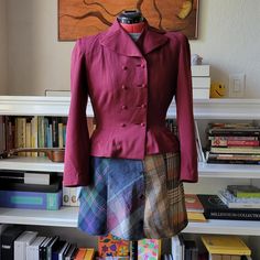 Gorgeous 1940s peplum jacket in a deep, on-trend burgundy. She's seen a little wear and tear but overall she's doing well for her age. There are some repairs that a good tailor could possibly take care of under the right arm, though the lining for the most part is in fantastic shape. There are a couple of small holes like the one pictured and the bottom button may need tightening just a bit, but keep that shank on there!  Flat measurements: Bust pit to pit: 18" Waist: 14" (dress form set to 26.5") Shoulder collar to seam: 6" Sleeve shoulder seam to wrist: 22" Length: 19"  As you can see from this being paired with a 90s plaid skirt, this is a timeless piece! 90s Plaid Skirt, Womens Suits, Peplum Jacket, Plaid Skirt, Dress Form, Plaid Skirts, Shoulder Sleeve, Take Care, Suits For Women