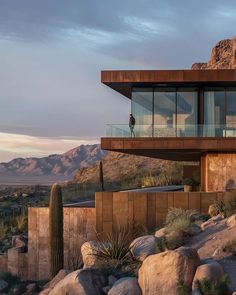 a house on top of a hill surrounded by rocks and cacti in the desert