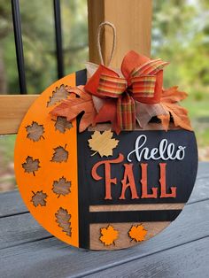 a wooden sign that says hello fall with leaves on it and a bow hanging from the front