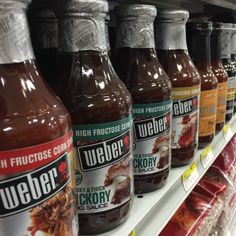 several bottles of ketchup sit on a shelf in a grocery store's aisle