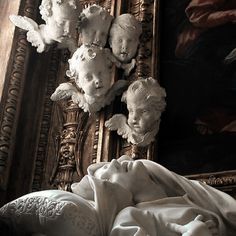 an image of statues on the wall in front of a mirror with angels above them