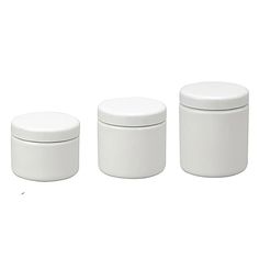 three white canisters with lids on a white background