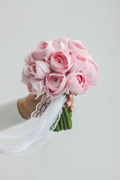 a bride's hand holding a bouquet of pink roses