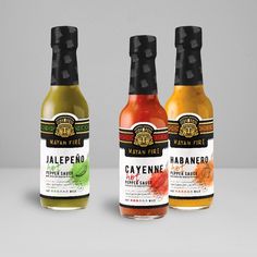 three bottles of jalepeno, cayenne and pepper sauce on a white surface