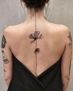 the back of a woman's neck with tattoos on her upper and lower back