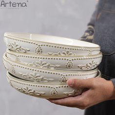 a person holding three white bowls in their hands