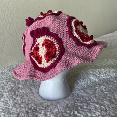 a crocheted pink hat with red and white hearts on it sitting on a head mannequin