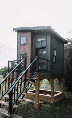 a small house with stairs leading up to the top floor and second story on stilts